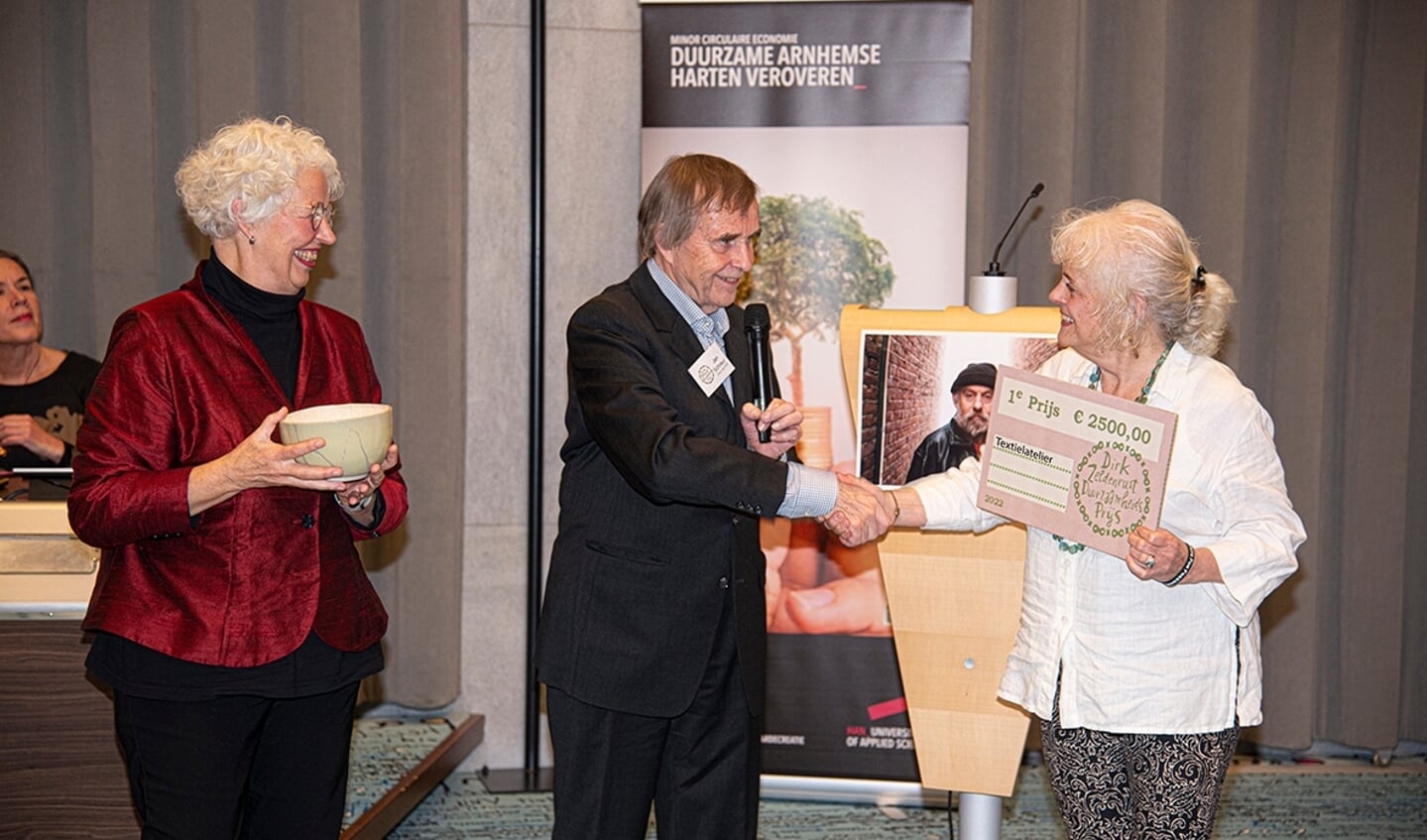 Jan Schreur, voorzitter van de Club van Dirk, reikt de eerste prijs uit aan Margriet Bleijenberg (links) en Gerrie Peters van het Textielatelier. 