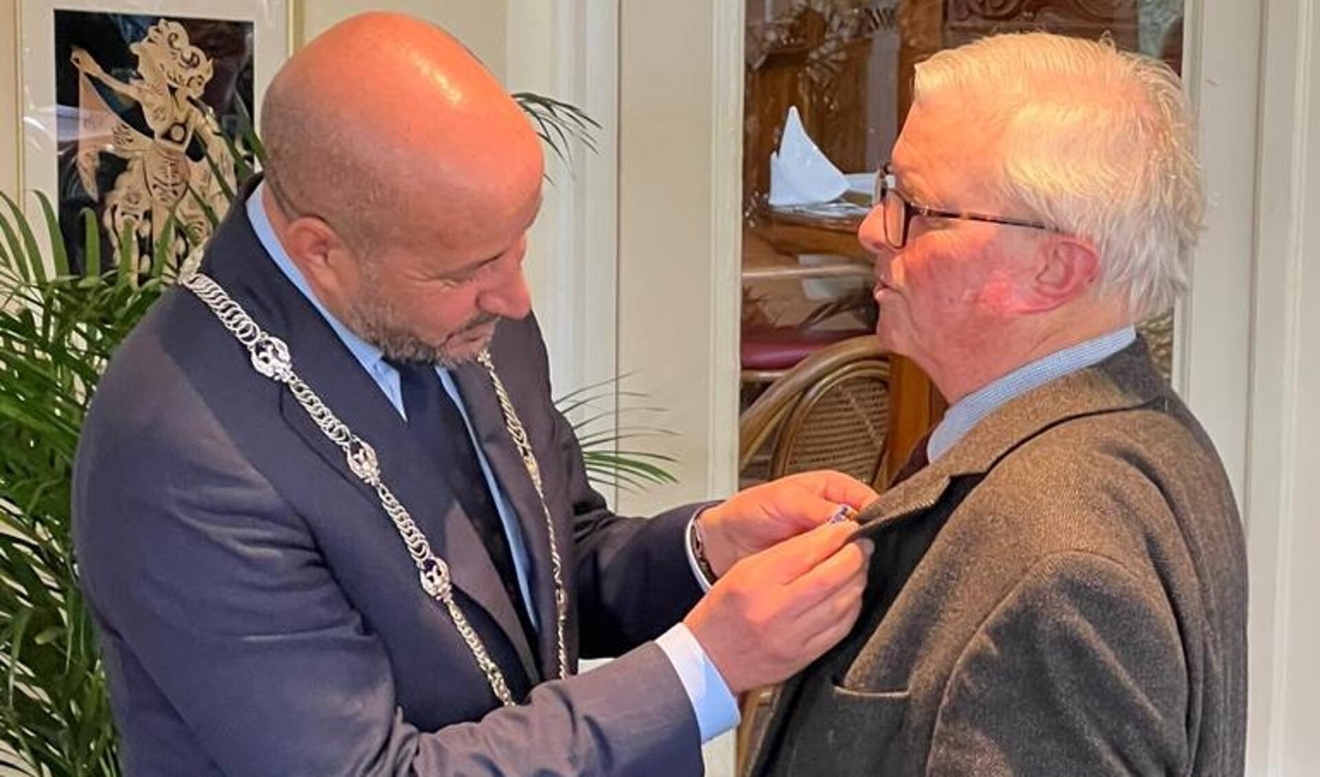 Burgemeester Ahmed Marcouch spelt bij Gijs Schut het lintje op dat hoort bij zijn benoeming tot Lid in de Orde van Oranje-Nassau.