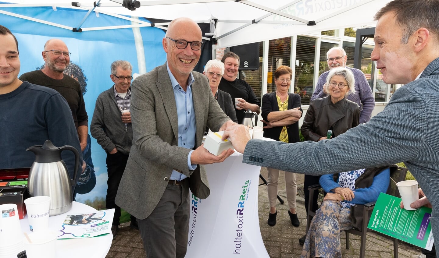 De heer Pietersen (links op de foto) en wethouder Wijnte Hol (rechts op de foto) onthullen het nieuwe haltebord bij Dorpshuis Beatrix in Slijk-Ewijk.
