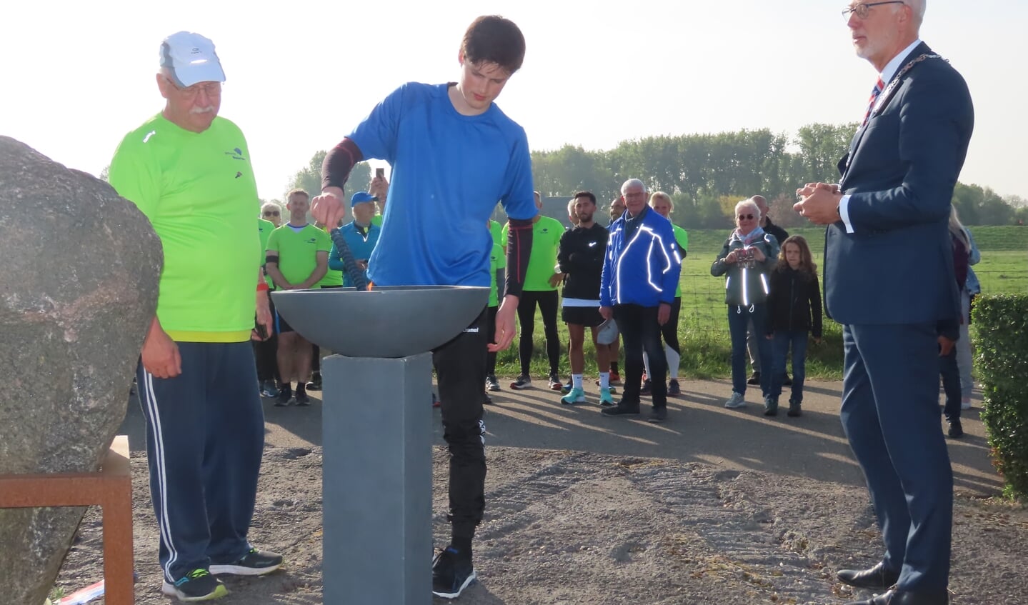 Het vuur wordt ontstoken. Burgemeester Arend van Hout kijkt toe.