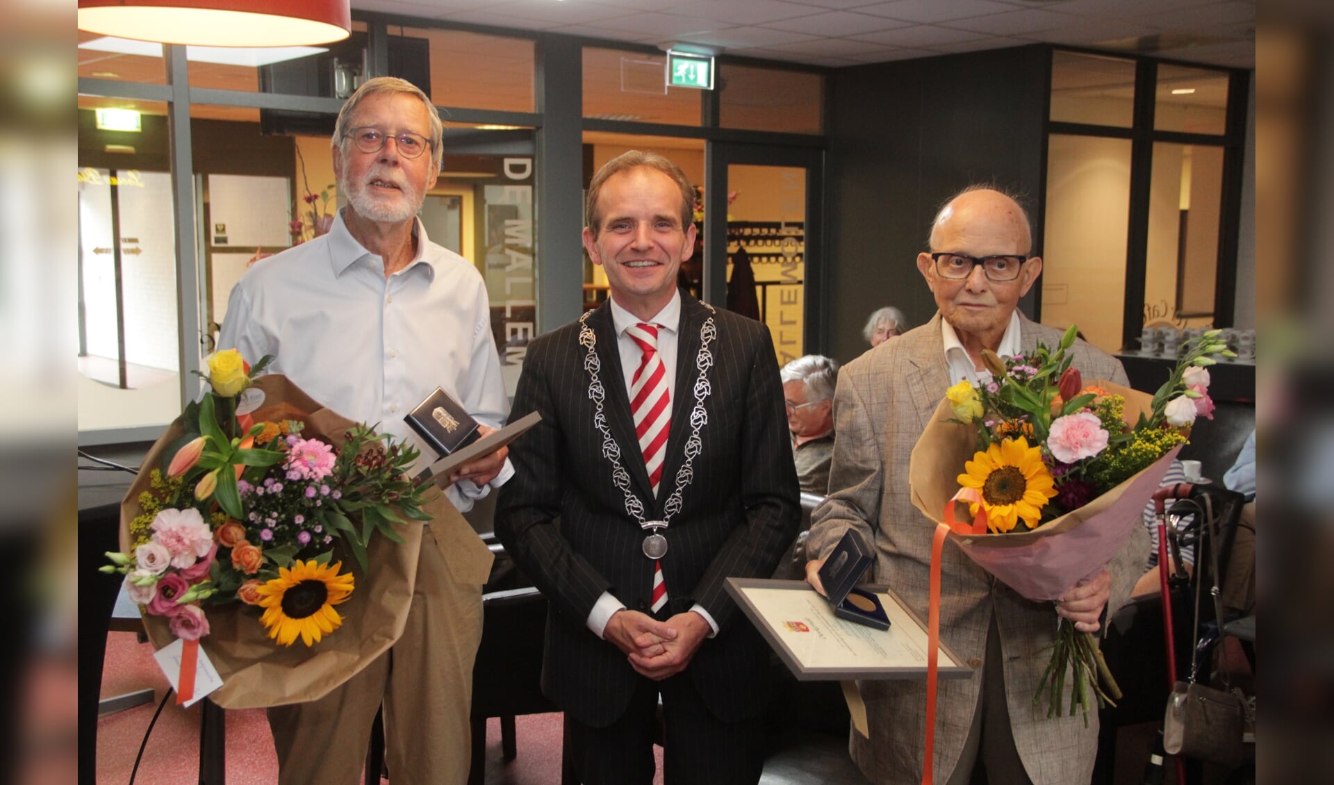 Burgemeester Slinkman te midden van de twee heren die een erepenning van de gemeente Berg en Dal gekregen hebben. 