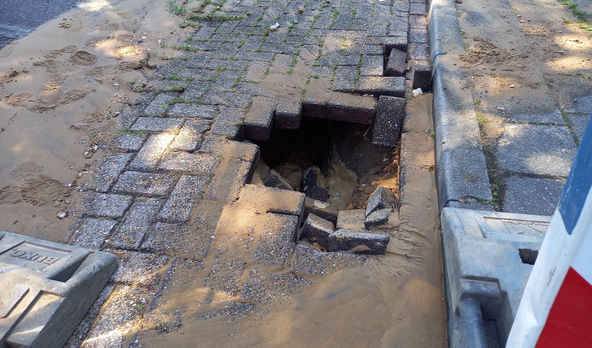 Waterleiding breuk slaat gat onder wegdek en trottoir. (foto: Joop Verstraaten)