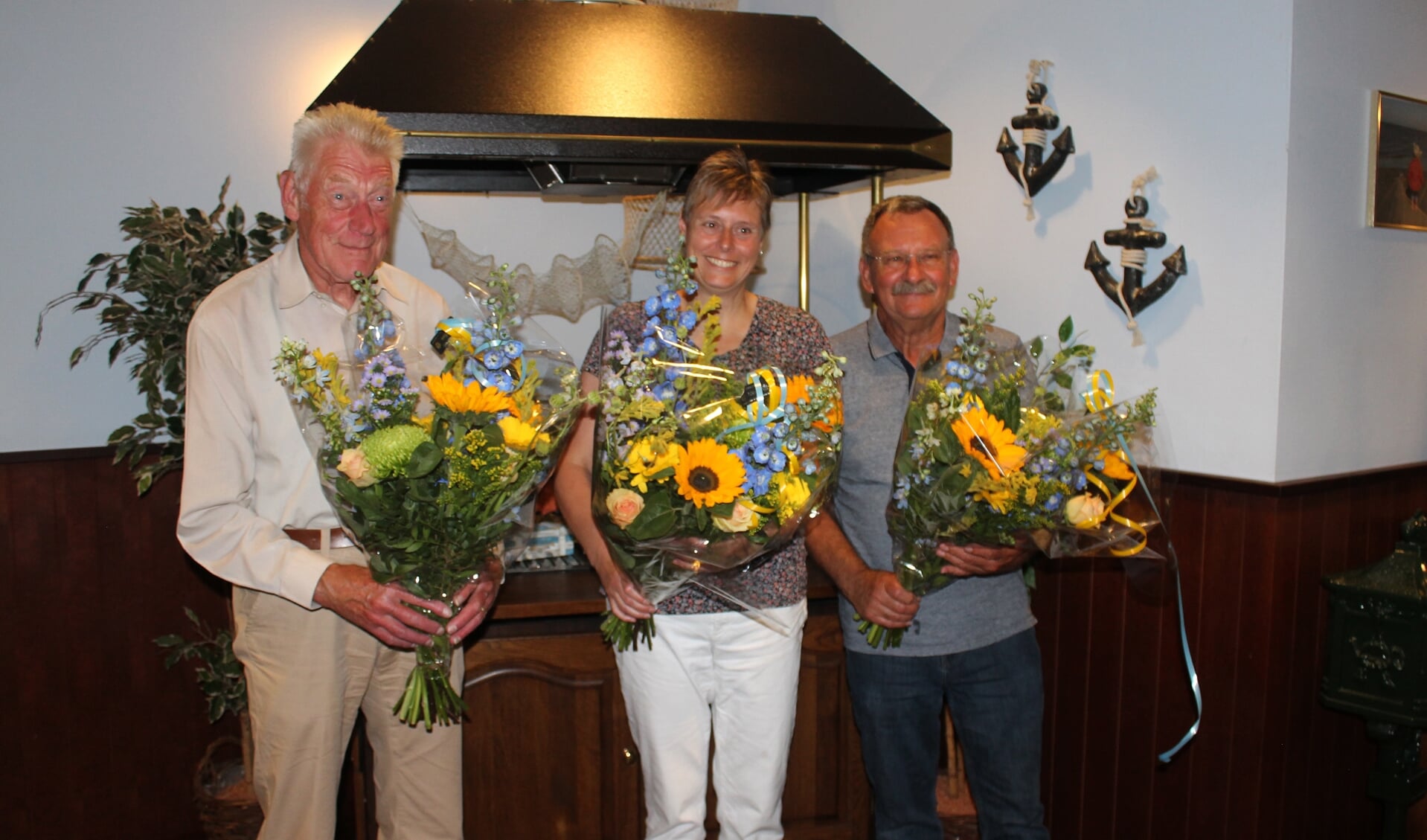 Jubilarissen met bloemen. Van links baar rechts: Frits Mennen, Ester Ruisch, Abel Hoegée.