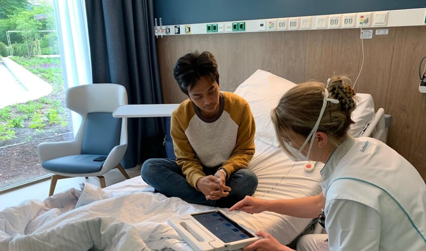 Een patiënt krijgt uitleg over gebruik tablet.