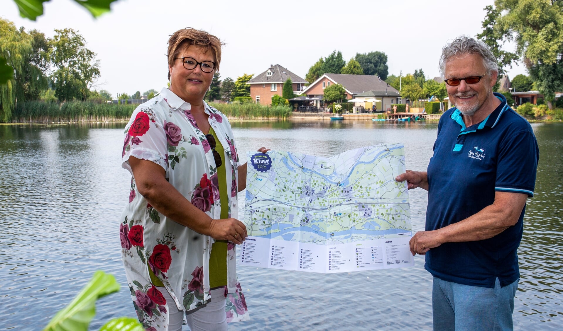 Wethouder Herma van Dijkhuizen (links) en Mark van der Vlerk met de recreatiekaart Neder-Betuwe op recreatiepark de Markplas in Opheusden. 