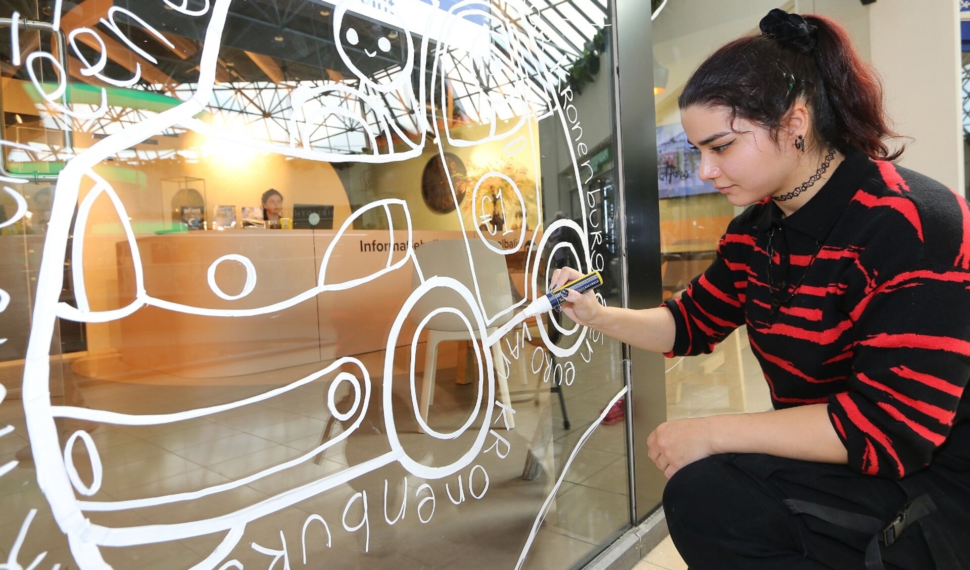 Een kunstenaar maakt een raamtekening in winkelcentrum Kronenburg.