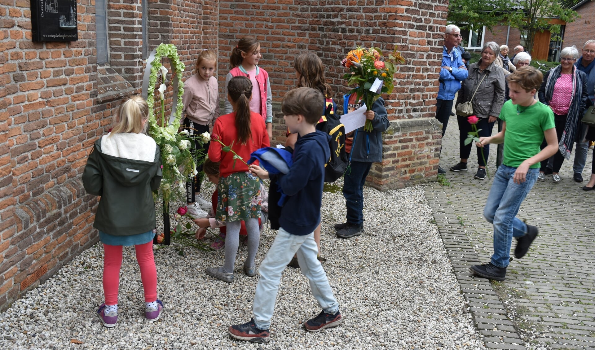 Kinderen van basisscholen De Lanteerne en De Zonnewende leggen bloemen bij het monument ter herinnering aan de Heese oorlogsdoden
