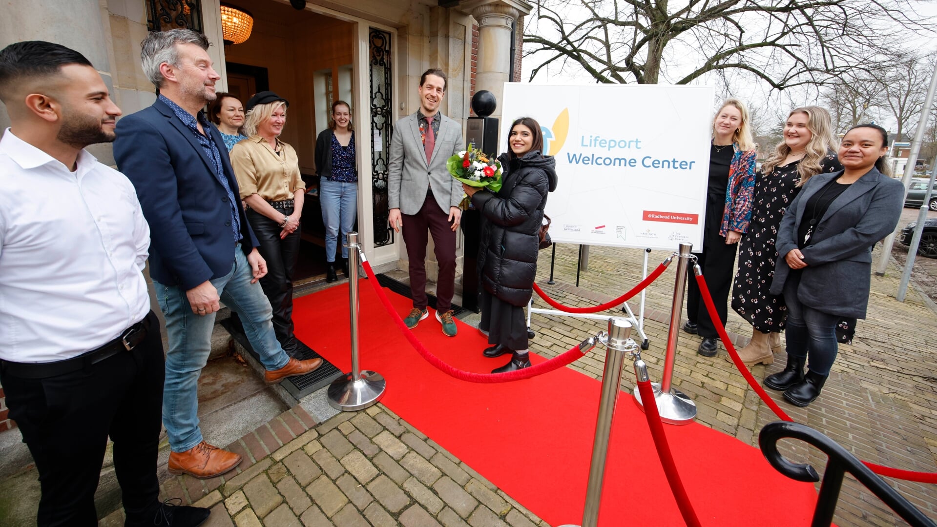 Maria Amjed uit Pakistan wordt als eerste bezoeker van Lifeport Welcome Center welkom geheten door medewerkers LWC, gemeente Nijmegen en IND.