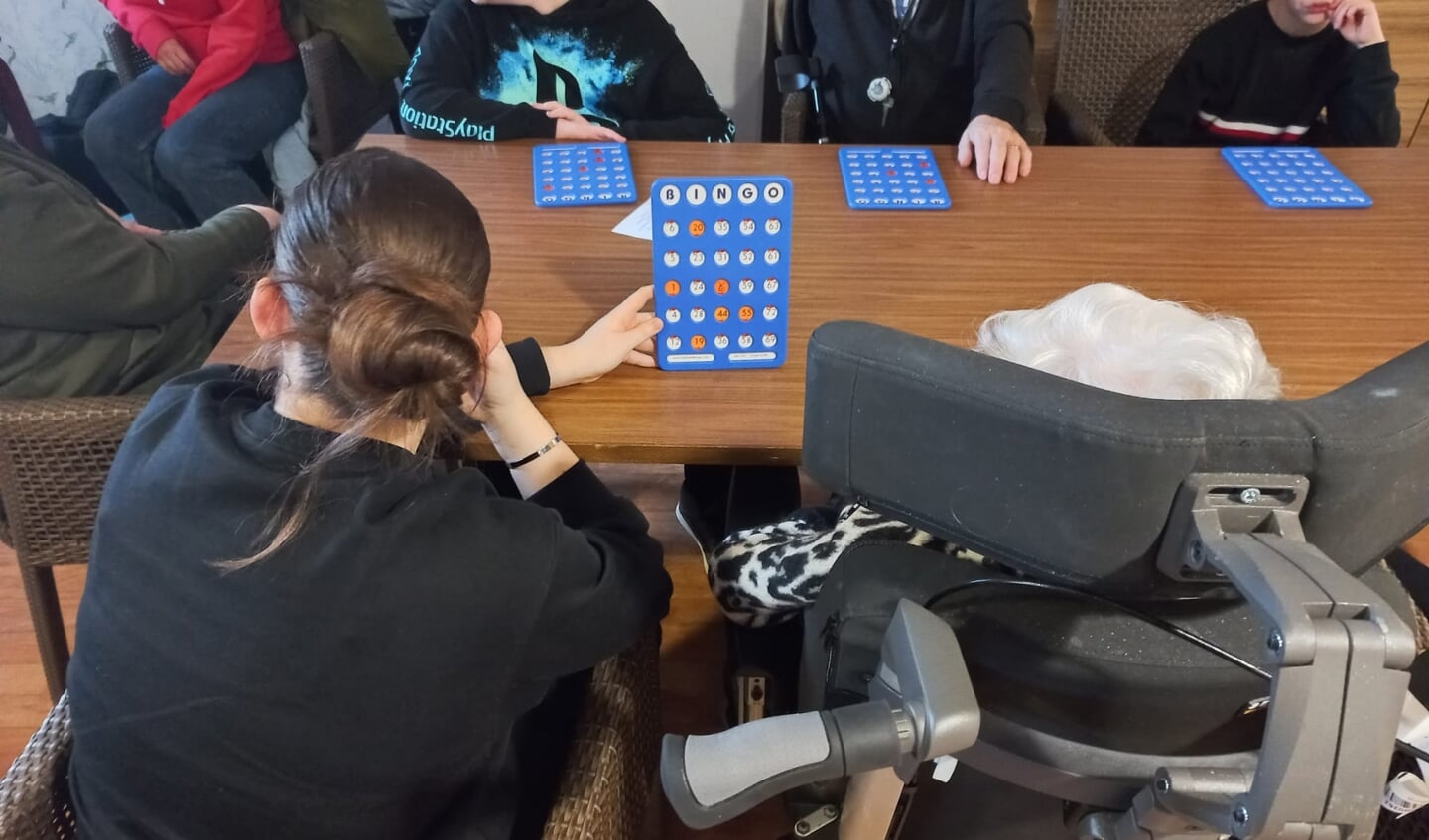 De kinderen helpen de senioren met het invullen van de bingokaart.