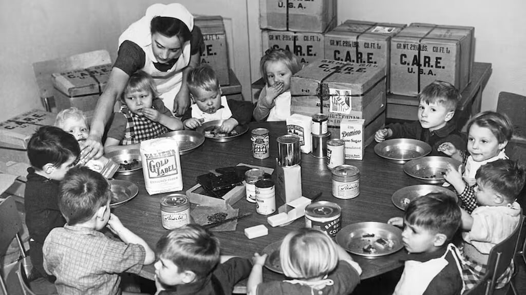 Een verpleegster voedt Nederlandse kinderen uit CARE-pakketten, circa 1953.