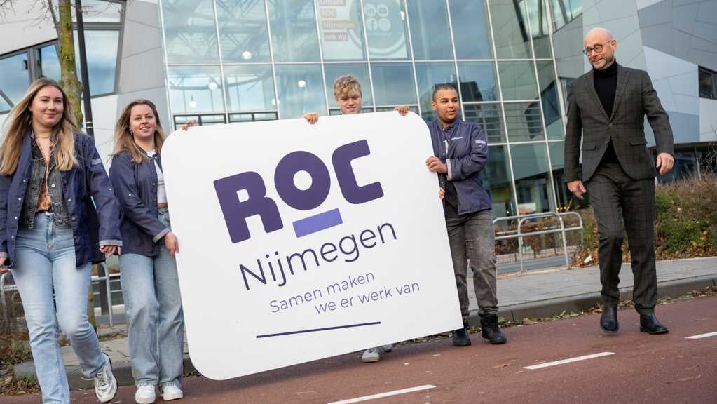 Bestuursvoorzitter Peter van Mulkom (rechts) met vier studenten van ROC Nijmegen, die de nieuwe signing naar het ROC-pand aan de Campusbaan in Nijmegen dragen.
