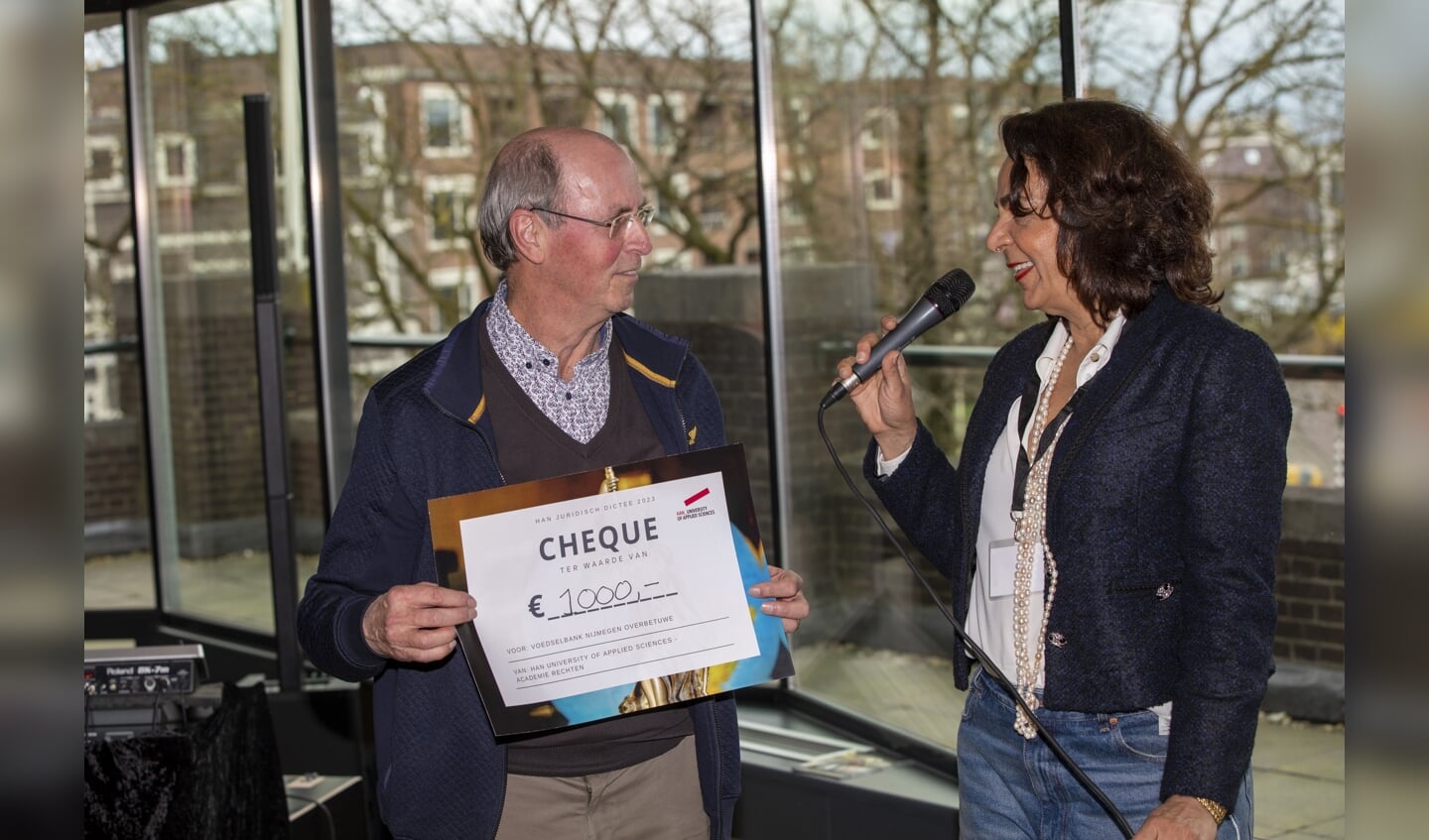 Jan van Halder, voorzitter van de Voedselbank Nijmegen-Overbetuwe neemt de cheque van 1000 euro in ontvangst door academiedirecteur Manon Eustatia. 