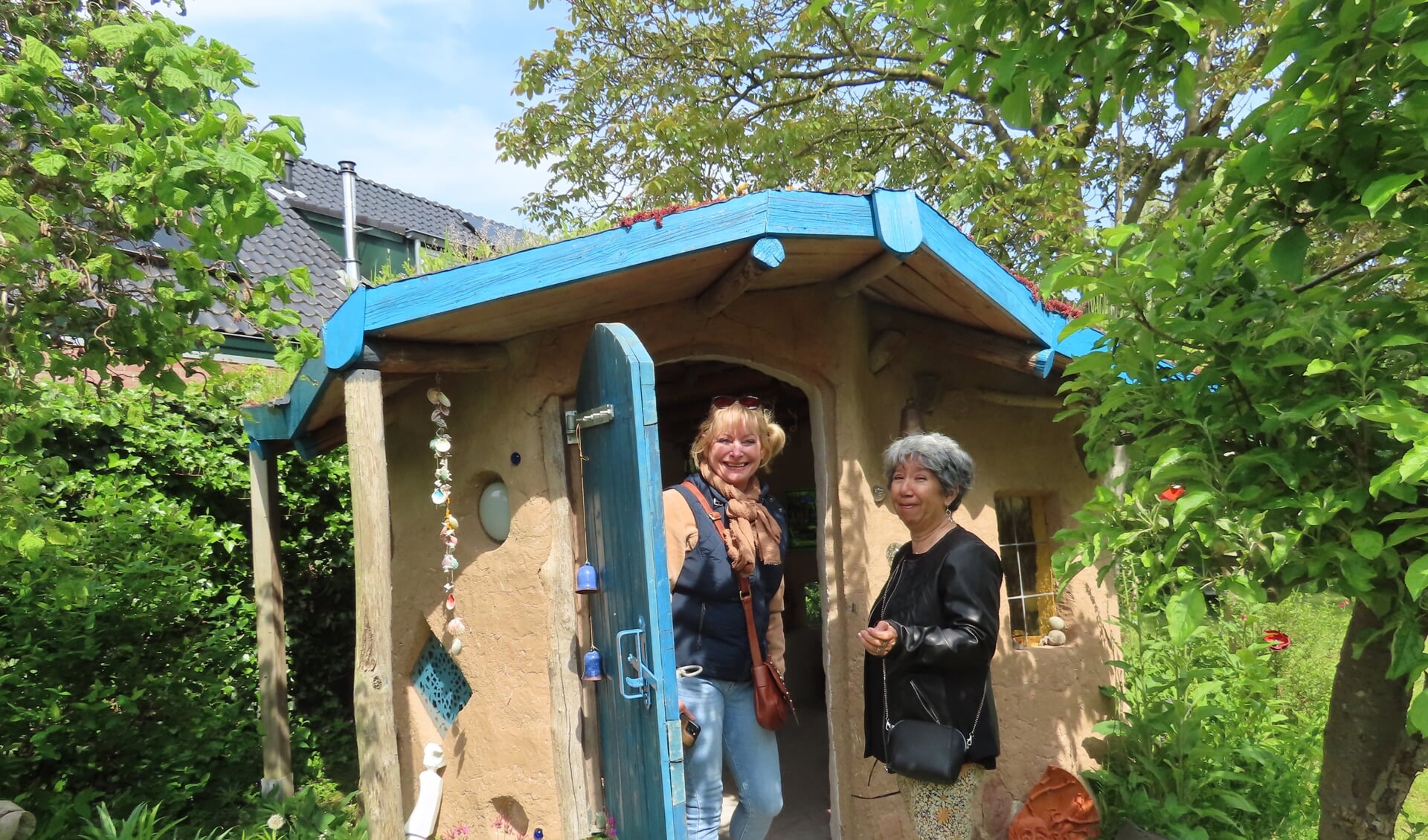 Anja en Yvonne betreden het lemen huisje in de tuin van Conny Koster
