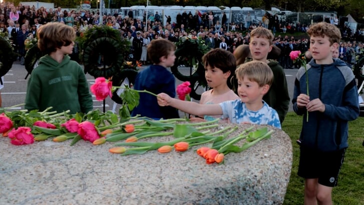 Scholieren leggen bloemen bij het monument. 