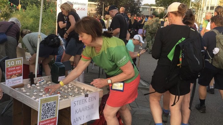 Wandelaars steken een kaarsje op.