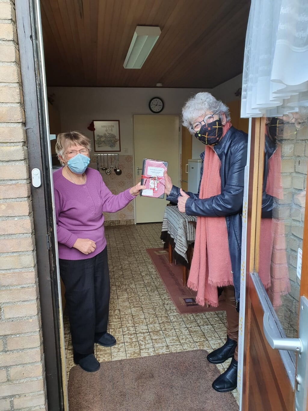 Marion Schouten, vrijwilligster Huiskamer van Elst overhandigt het kookboek aan een blije Ans Schoonderbeek. (foto: Ton Schouten)