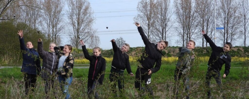 Basisschoolleerlingen gooien biodiversiteitsbommen op het Plaksche Veld. (foto: Rietje van Dalen SLN)