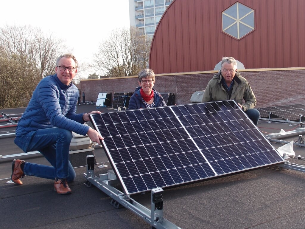 Het plaatsen van het 'eerste zonnepaneel' op het dak van de Ontmoetingskerk door drie leden van de werkgroep Groene Kerk PGR. Van links naar rechts: Frans Jansen, Jolande Oldekamp en Roelof de Jong.