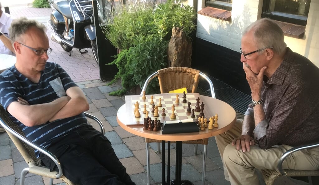 Schaken op het terras van het Môks Café. Rob Boesten en Anton Meeuwsen (r) bekijken een lastige stelling. (foto: Huub Blom)