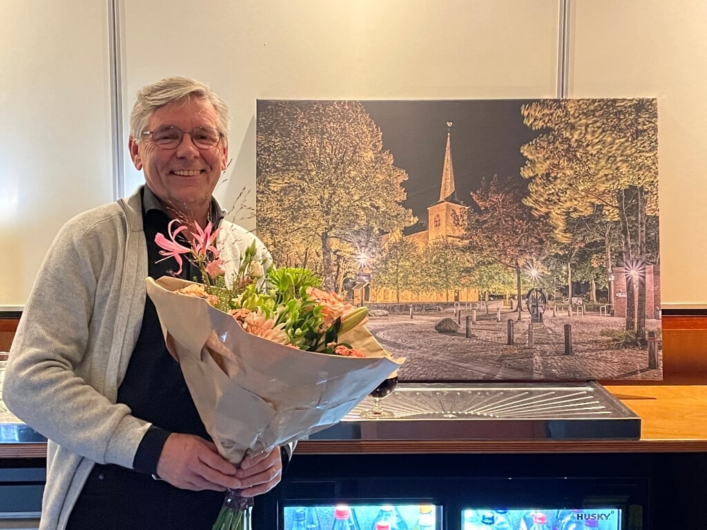 Vincent Arts met op de achtergrond een foto van het dorpsplein Heumen sls geschenk. (eigen foto)