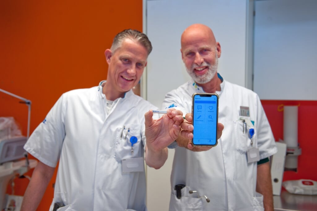 Cardioloog Erwin Zegers (links) en verpleegkundig specialist Jan Elders tonen de hartritmemonitor en de bijbehorende app. (Foto: CWZ Nijmegen)