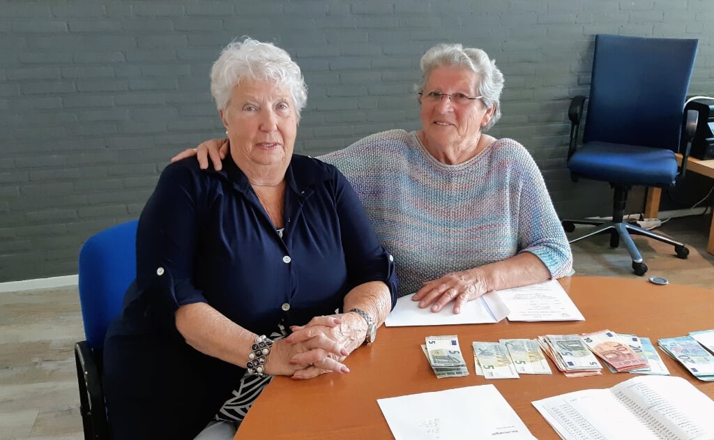 Geertrui (rechts) overhandigt het donateursgeld aan de penningmeester. (foto: Arie Kuhlman)