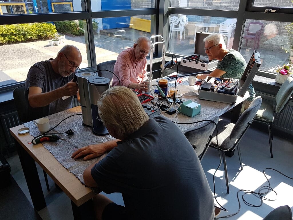 De heren van het Repaircafé Lingewaard aan de slag met defecte apparaten. (foto: Wil van den Hurk)