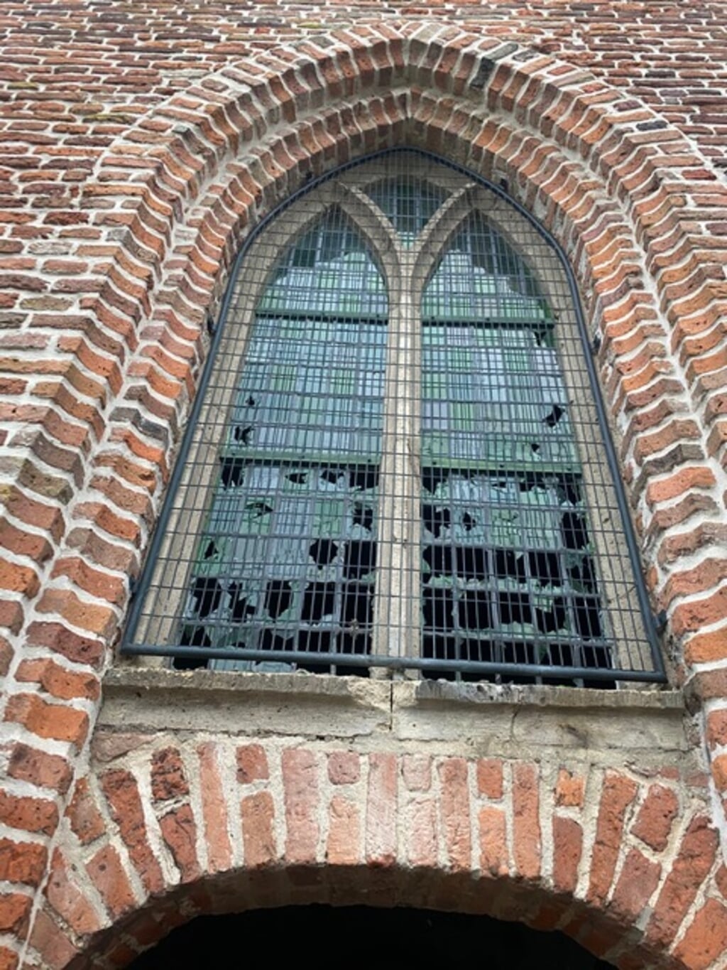 Het glas-in-loodraam van de oude kerktoren van de protestantse kerk in de Kerkstraat in Groesbeek, boven de hoofdingang van de kerk.(foto: Hennie Smit)
