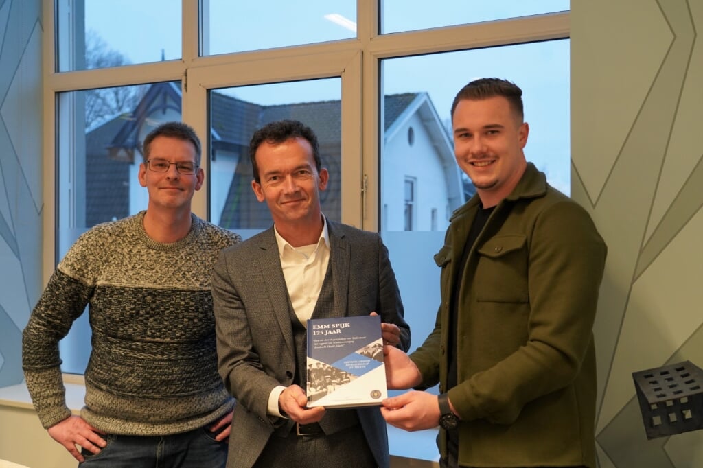 Luciën van Riswijk ontvangt het boek over Spijk van Mark Pastoors (links) en Yoeck Heijmen. (Foto: Carla Droste)