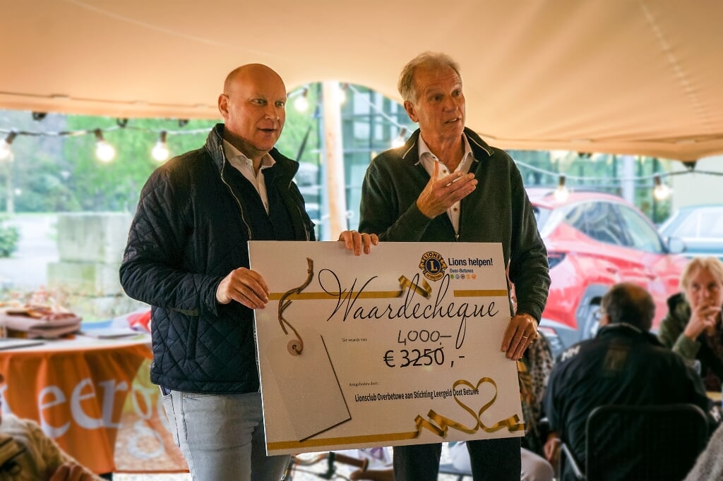 Cor Hendriks neemt cheque in ontvangst uitgereikt door Jan-Jaap Zollinger namens de Lions rally organisatie. (foto: Lions Over-Betuwe)