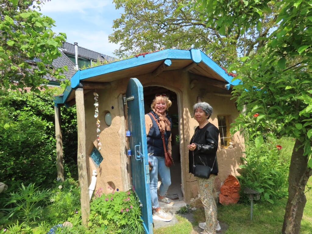 Anja en Yvonne betreden het lemen huisje in de tuin van Conny Koster