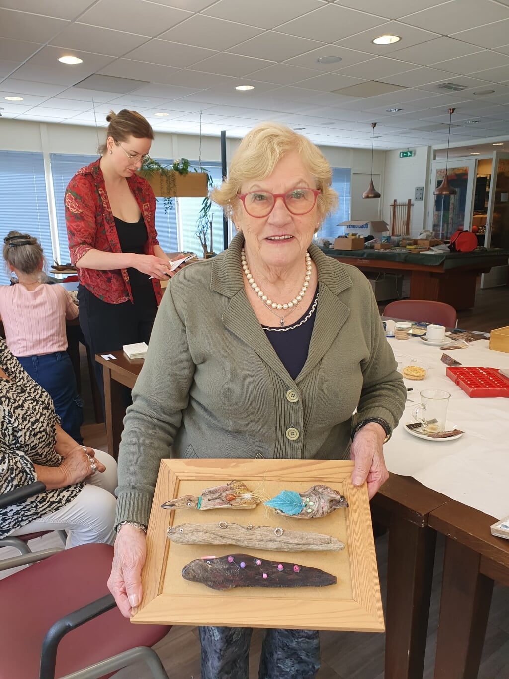 De 87-jarige Lucy toont haar kunstwerkjes van hout.