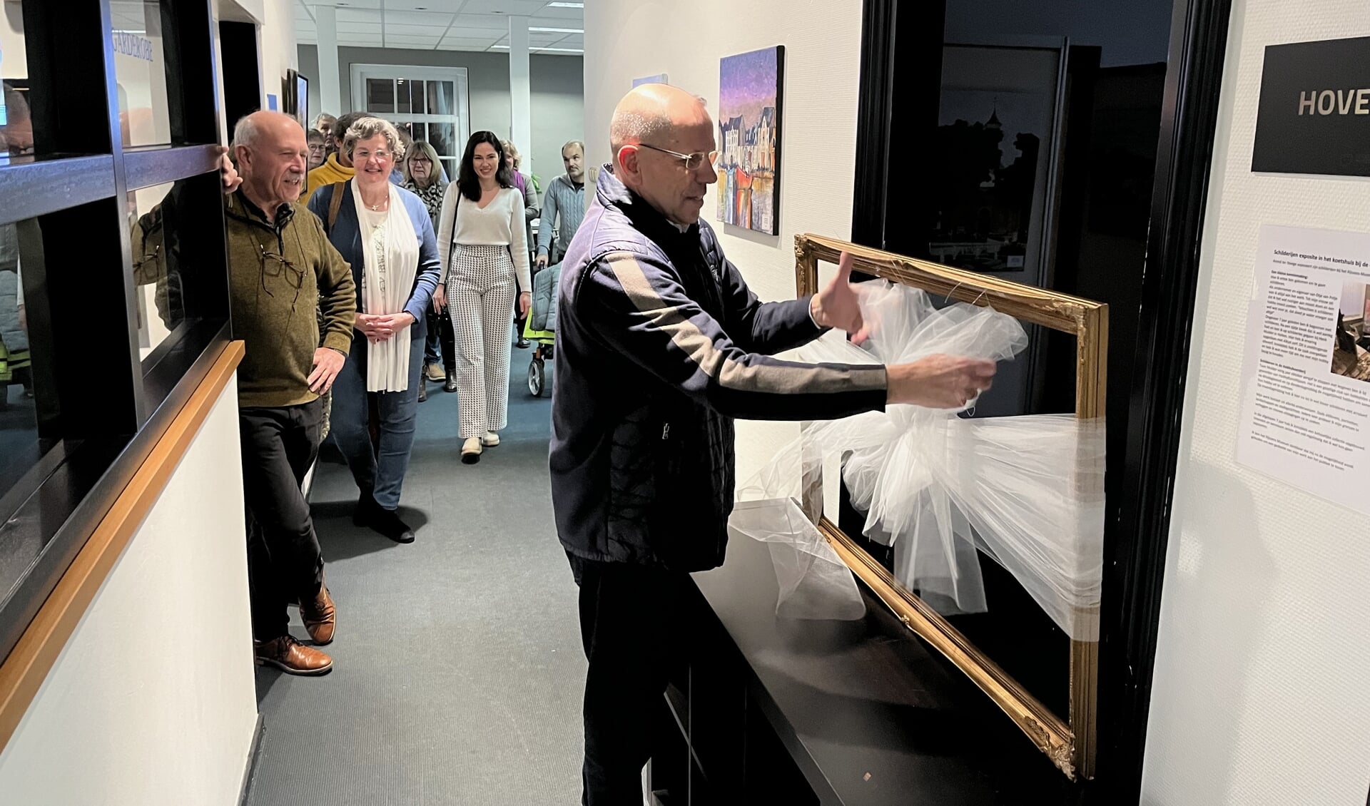 Arend ter Steege opent zijn expositie door de strik te verwijderen. Links kijkt collega-kunstschilder Rien van Driel toe, daarnaast moeder en dochter Ter Steege.