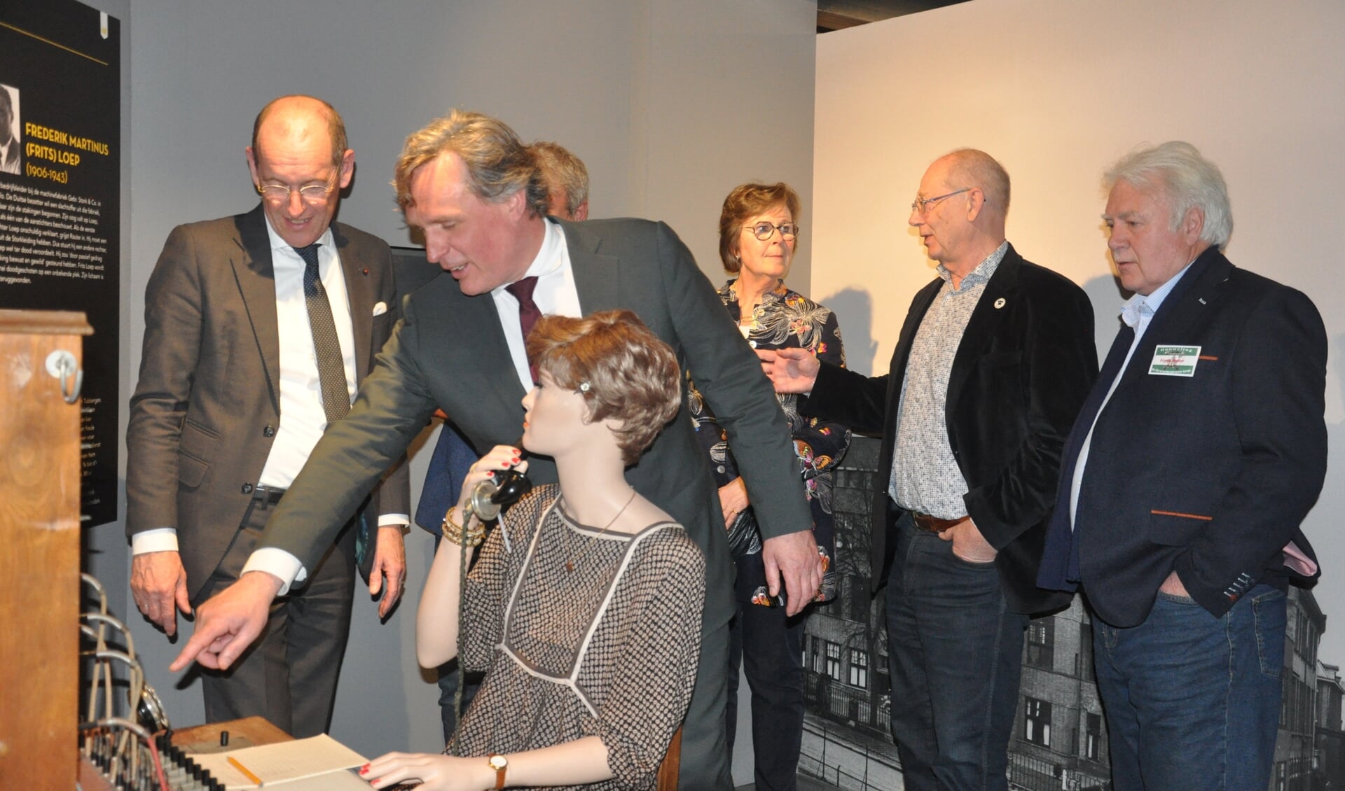 Burgemeester Jorrit Eijbersen en andere belangstellenden krijgen uitleg hoe de draadtelefoon van Femy Efftink werkte. 