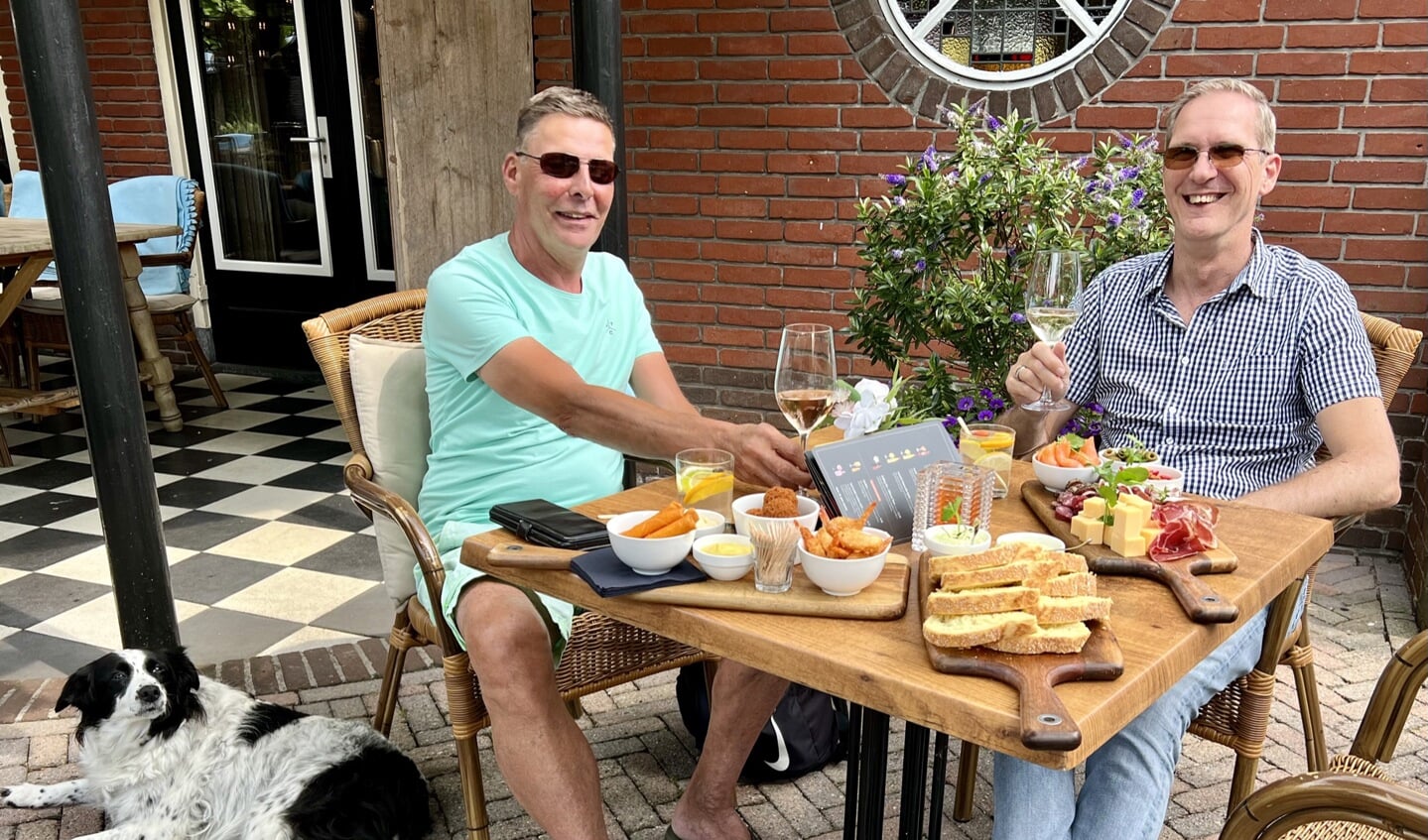 Twee gasten met hond: Vaste gasten Erik de Reuver (links) en Leon Berkenbosch (rechts) genieten van een wijntje en de borrelplank. 