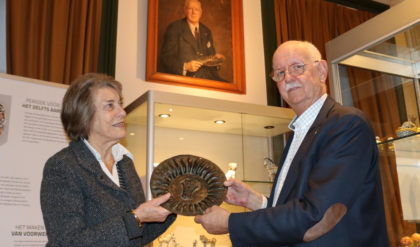 Voorzitter van het museumbestuur, Jan Bakker, neemt het Van Heelbord in ontvangst van mevrouw Rethmeier-Jordaan. Boven de vitrine het portret van Van Heel met bord. 