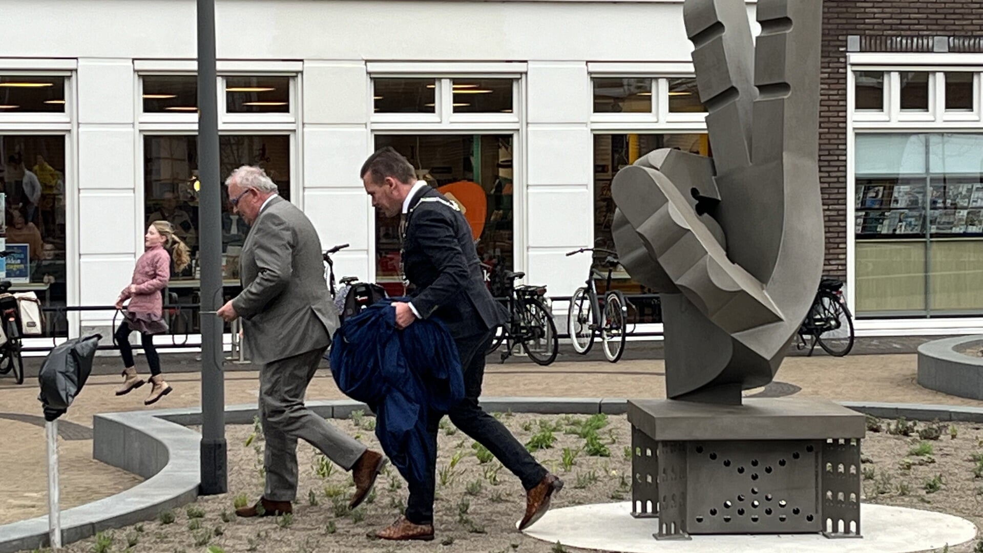 Oud-burgemeester Arco Hofland (links) en burgemeester Jurgen van Houdt lopen na de onthulling van het beeld weer terug naar hun plaats.